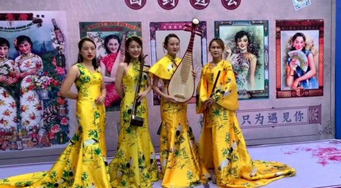 文博会中丝园分会场旗袍女子民乐演奏组合在“回到过去”影墙流连